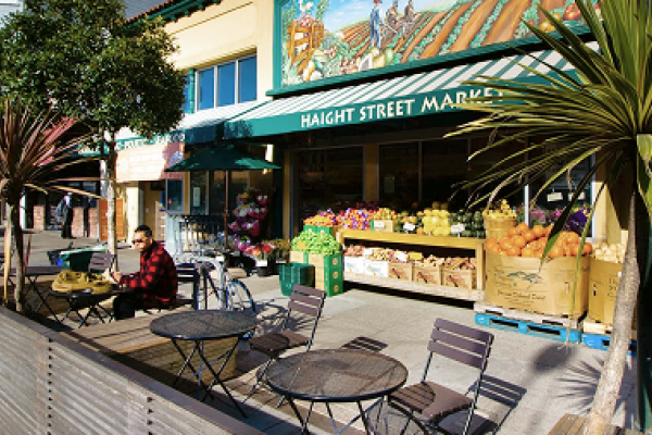 Outdoor seating and fresh produce displayed in front of Haight Street Market on a sunny day.