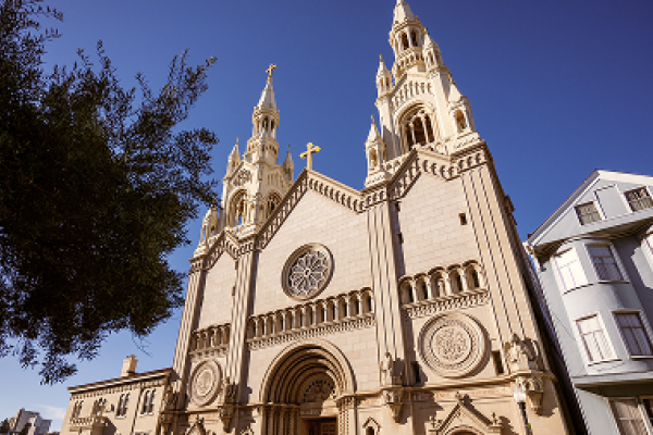A large, ornate church with two tall towers and a rose window, set against a clear blue sky.