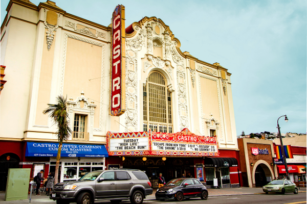 Historic Castro Theatre in San Francisco, with cars parked out front and nearby shops visible.