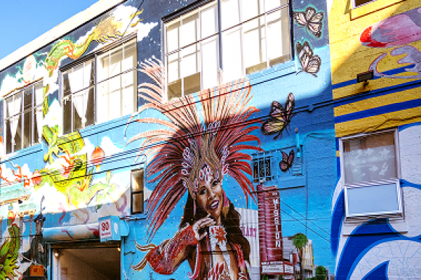 Colorful mural on a building featuring a woman in a feathered headdress, butterflies, and various vibrant designs.