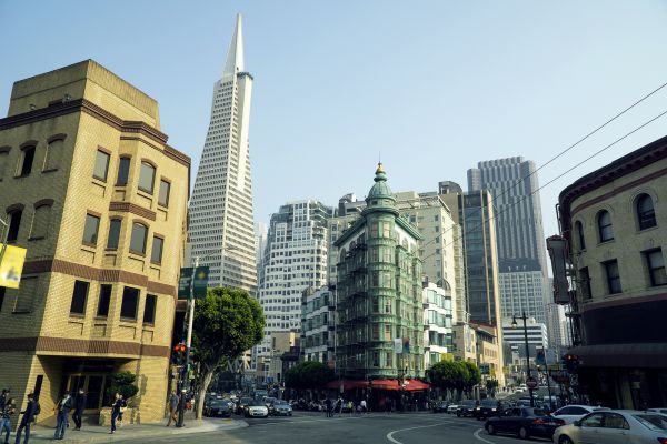 San Francisco city street with historic buildings and the Transamerica Pyramid in the background on a clear day.